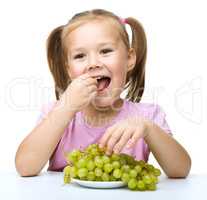 Little girl is eating grapes