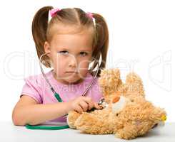 Little girl is playing with her teddy bear