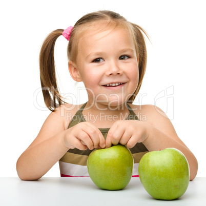 Little girl with two green apples