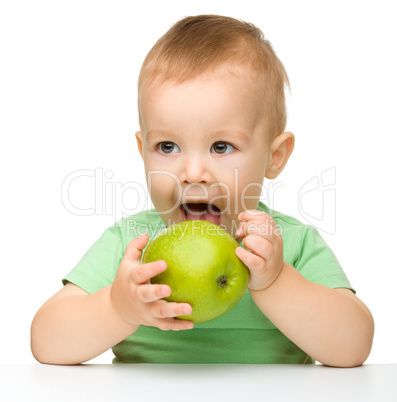 Little child is eating green apple