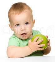 Little child is eating green apple