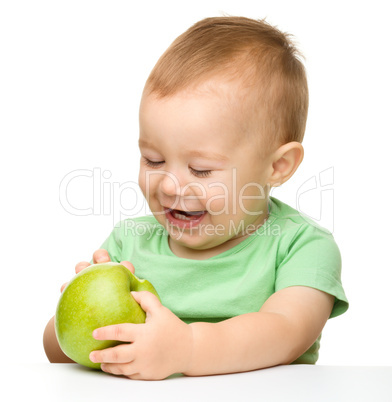 Little child is eating green apple