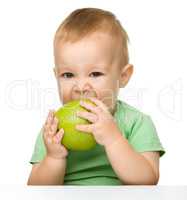Little child is eating green apple