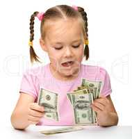 Cute little girl is counting dollars