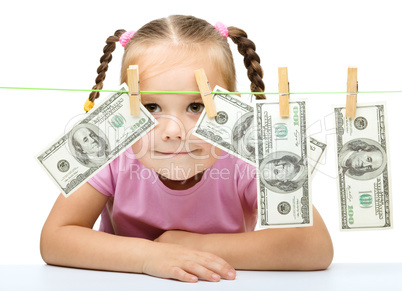 Cute little girl is playing with paper money