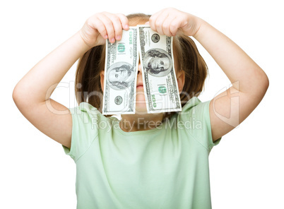 Little girl is covering her eyes with dollars