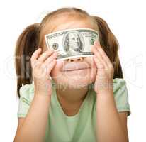 Little girl is covering her eyes with dollars
