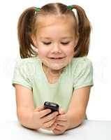 Cute little girl is playing with cell phone