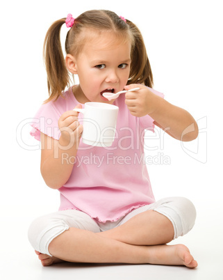 Cute little girl is eating yogurt