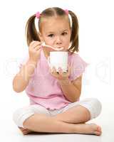 Cute little girl is eating yogurt