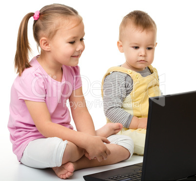 Little girl and boy are looking at laptop