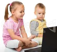 Little girl and boy are looking at laptop