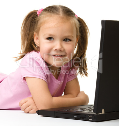 Cute little girl is sitting on floor with laptop
