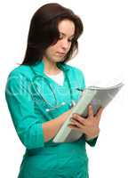 Young attractive woman doctor is writing