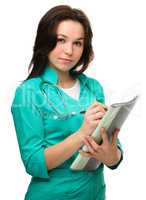 Young attractive woman doctor is writing