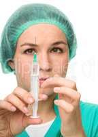Young nurse is preparing syringe for injection