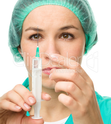 Young nurse is preparing syringe for injection