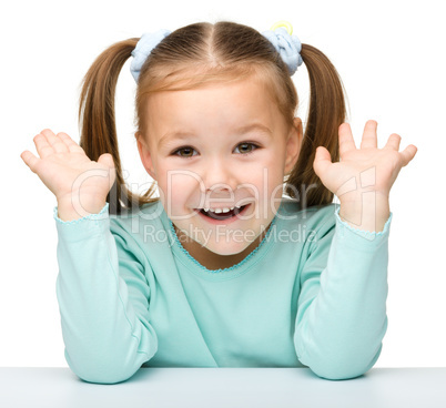 Happy little girl sits at a table and smile