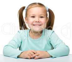 Happy little girl is sitting at the table