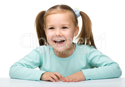 Happy little girl sits at a table and smile