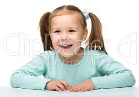 Happy little girl sits at a table and smile