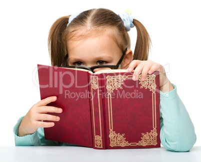 Little girl is hiding behind a book
