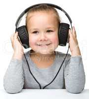 Cute little girl enjoying music using headphones