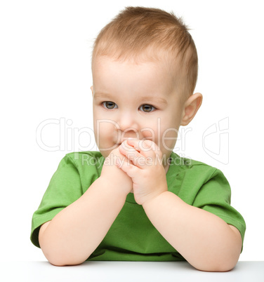 Pensive little boy support his head with hand