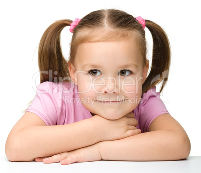 Happy little girl sits at a table and smile