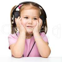 Little girl is enjoying music using headphones