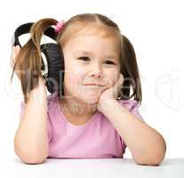 Cute little girl is bored to listen music