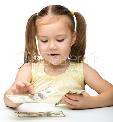 Cute cheerful little girl is counting dollars