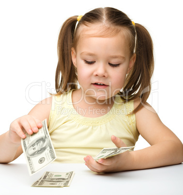 Cute cheerful little girl is counting dollars