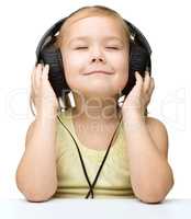 Little girl is enjoying music using headphones