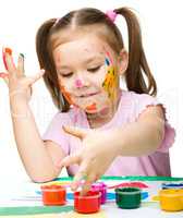 Portrait of a cute girl playing with paints