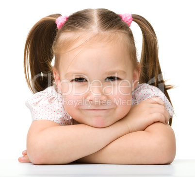 Happy little girl sits at a table and smile