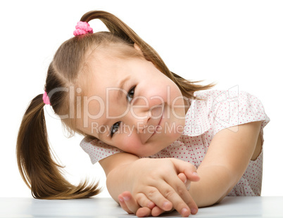 Happy little girl sits at a table and smile