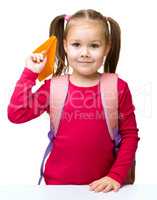 Schoolgirl with backpack throwing a paper airplane