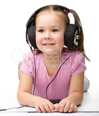 Cute little girl enjoying music using headphones