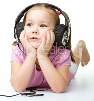 Cute little girl enjoying music using headphones