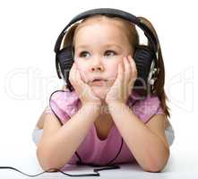 Cute little girl enjoying music using headphones