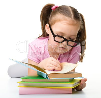 Cute little girl reads a book wearing glasses