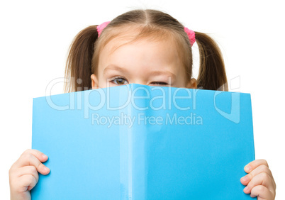 Cute little girl is hiding behind a book