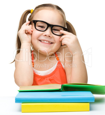 Cute cheerful little girl reading book