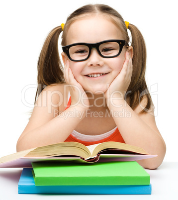 Cute cheerful little girl reading book