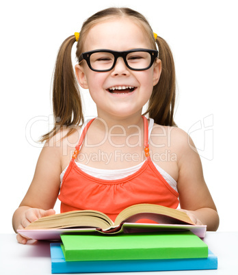 Cute cheerful little girl reading book