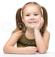 Happy little girl is sitting at a table and smile
