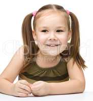 Happy little girl sits at a table and smile