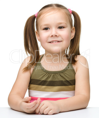 Happy little girl sits at a table and smile