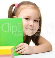 Cute little girl is hiding behind a book